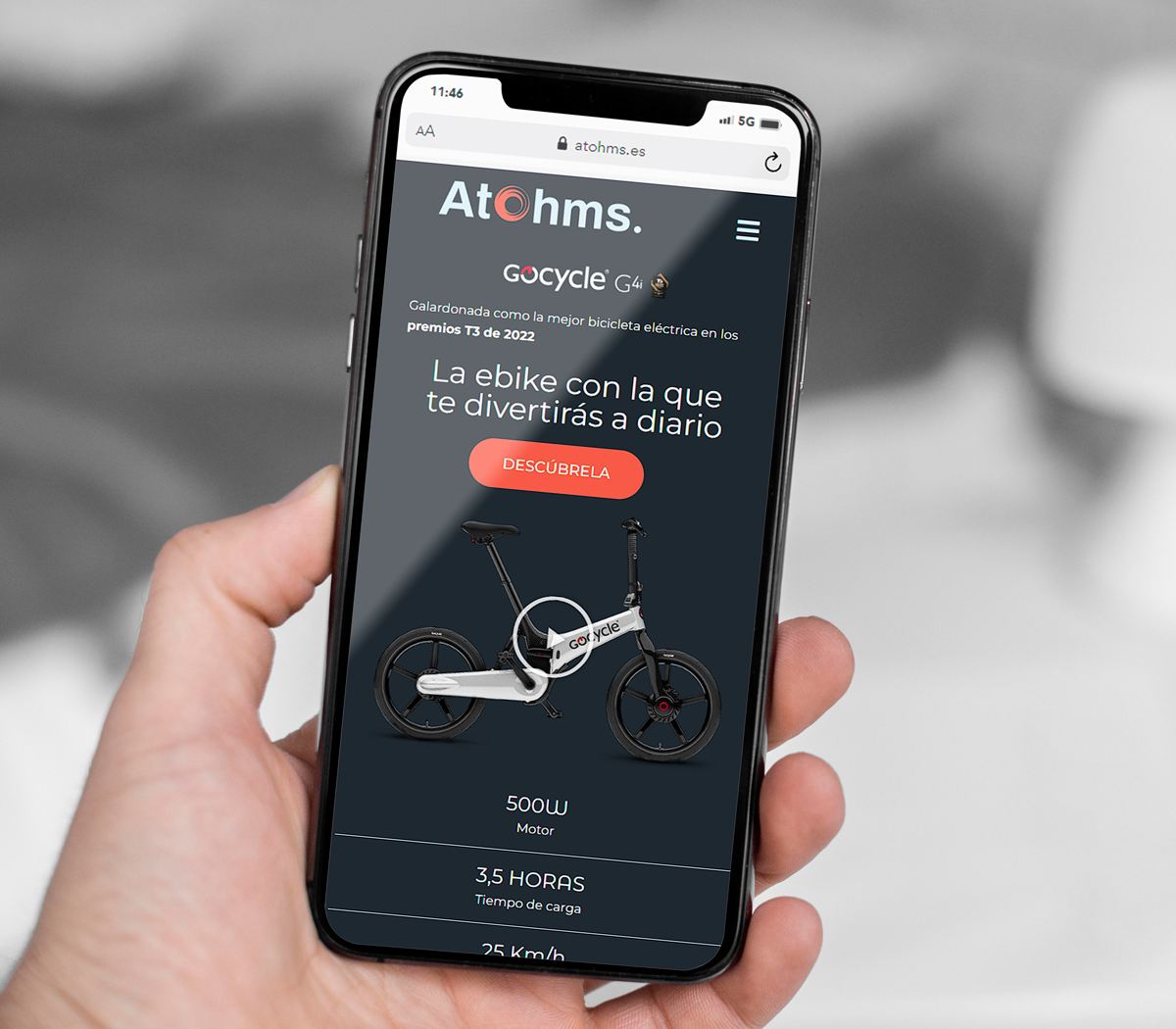 Mano de hombre con móvil en ella con web de Atohms abierta